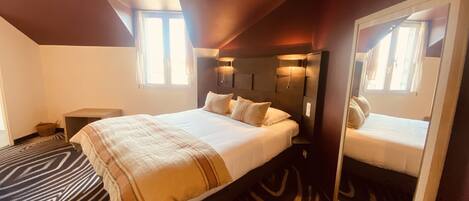 Habitación de hotel con una cama grande, un cabecero con iluminación integrada, una alfombra con estampado de cebra y un espejo en la pared.