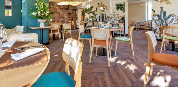 A restaurant interior with wooden furniture, tables set with wine glasses, and potted plants. - Le Relais des Gourmands (Gramat)
