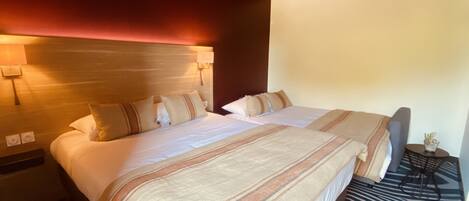 Una habitación de hotel con una cama grande, una mesita de noche, una lámpara y una pequeña mesa con un jarrón.