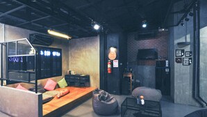 A modern living room with a wooden bench, black seating, and a brick wall.
