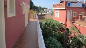 A red building with a balcony, a flag, and a sign indicating it's a hostel. - Hostal Alhaja Playa (El Puerto de Santa Maria)