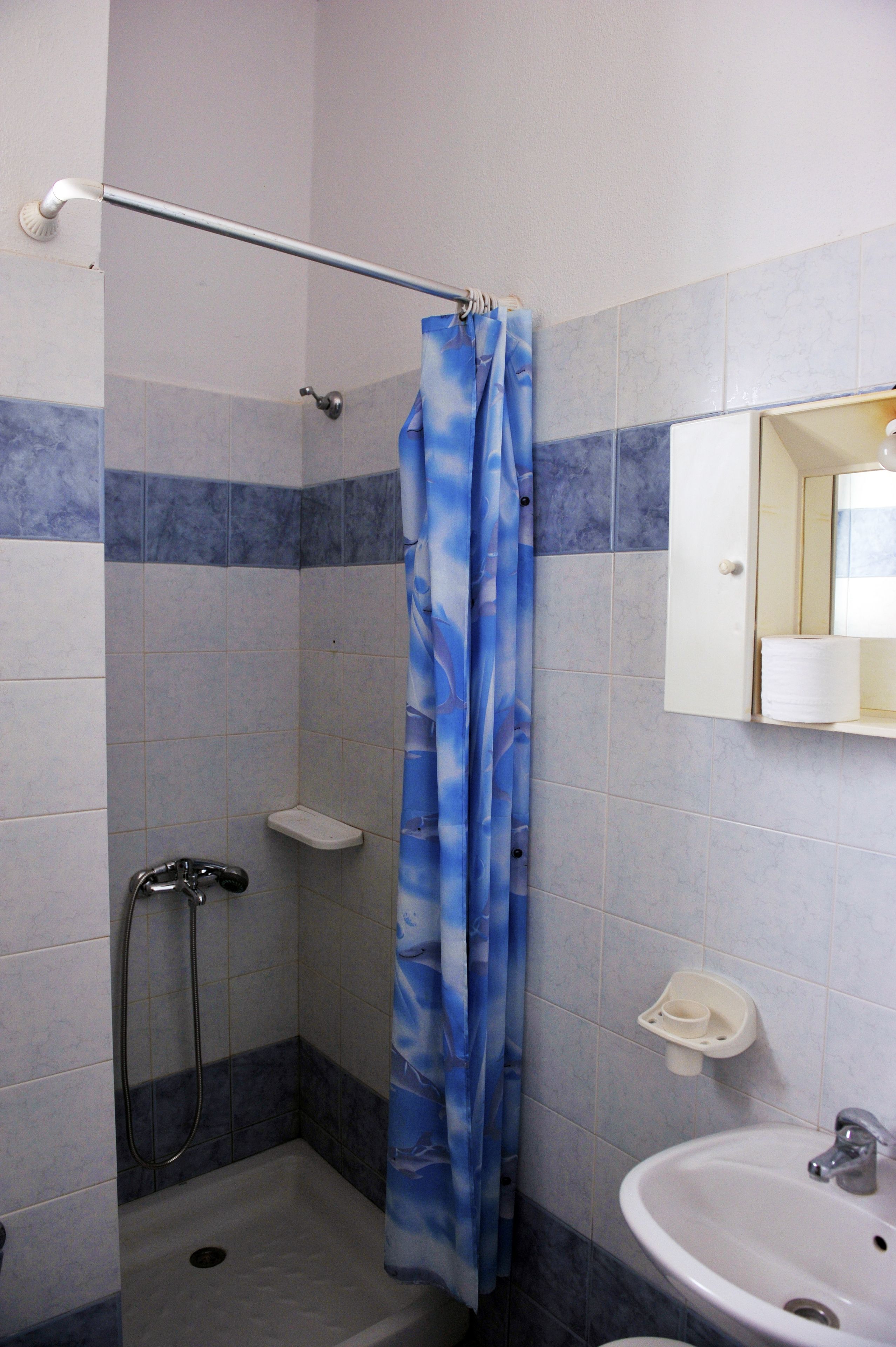 Un baño con ducha, lavamanos y espejo.