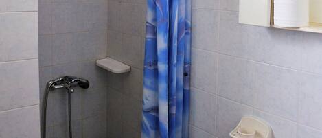 Un baño con ducha, lavamanos y espejo.