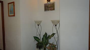 Un pasillo con una planta en maceta, dos lámparas de pared y un cuadro en la pared.