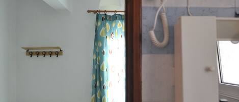 A room with a bed, a wooden headboard, a hanging light fixture, a telephone, and a bathroom with a toilet.
