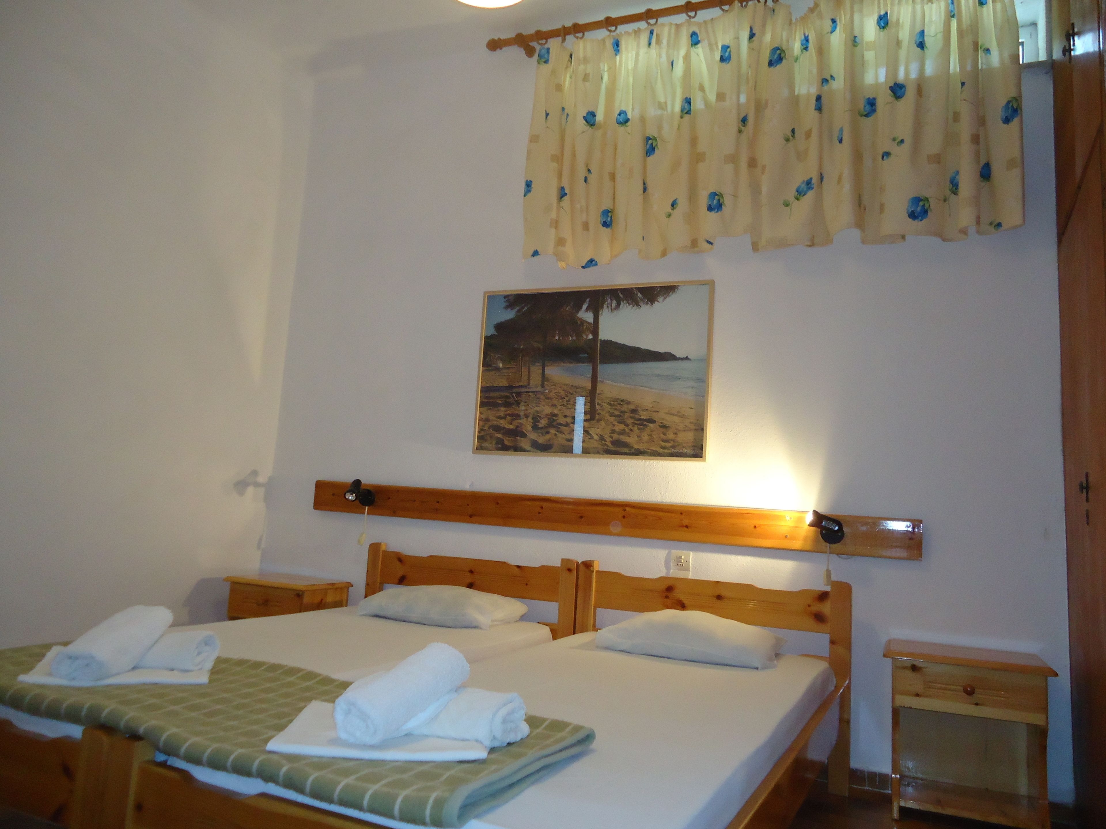 Ein Hotelzimmer mit einem Bett, einem Holzkopfende, einem Nachttisch und einem Bild mit einer Strandansicht.