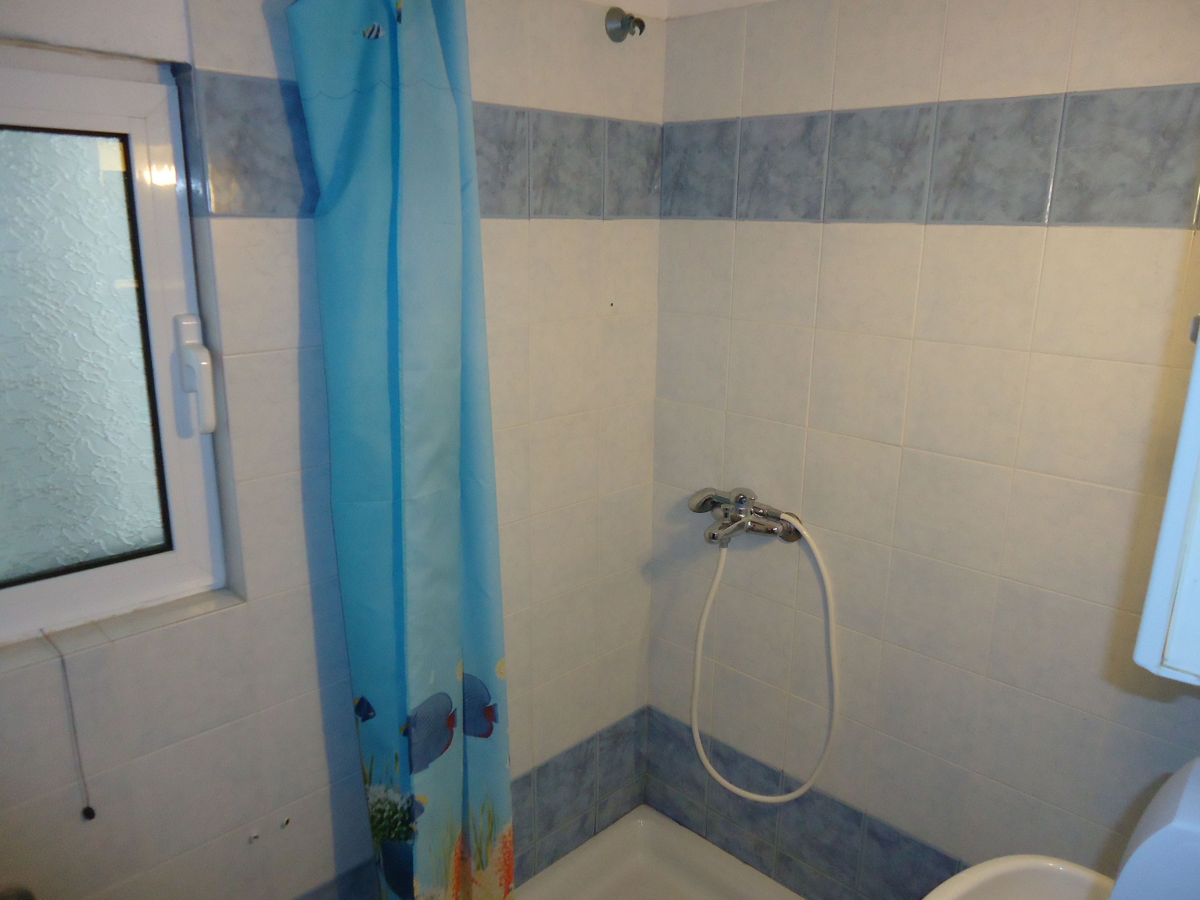 Un baño con ducha, ventana e inodoro.