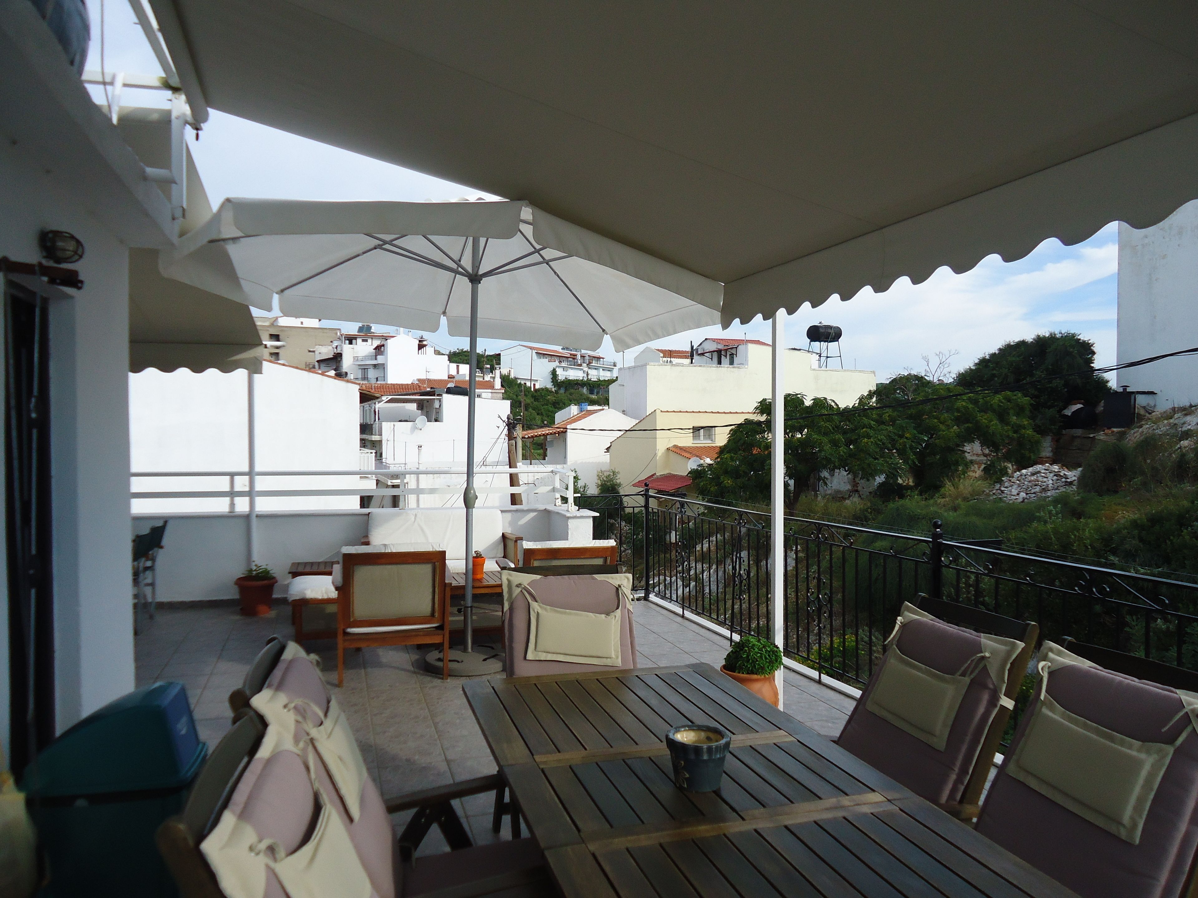 A covered outdoor seating area with tables and chairs, umbrellas, and potted plants.