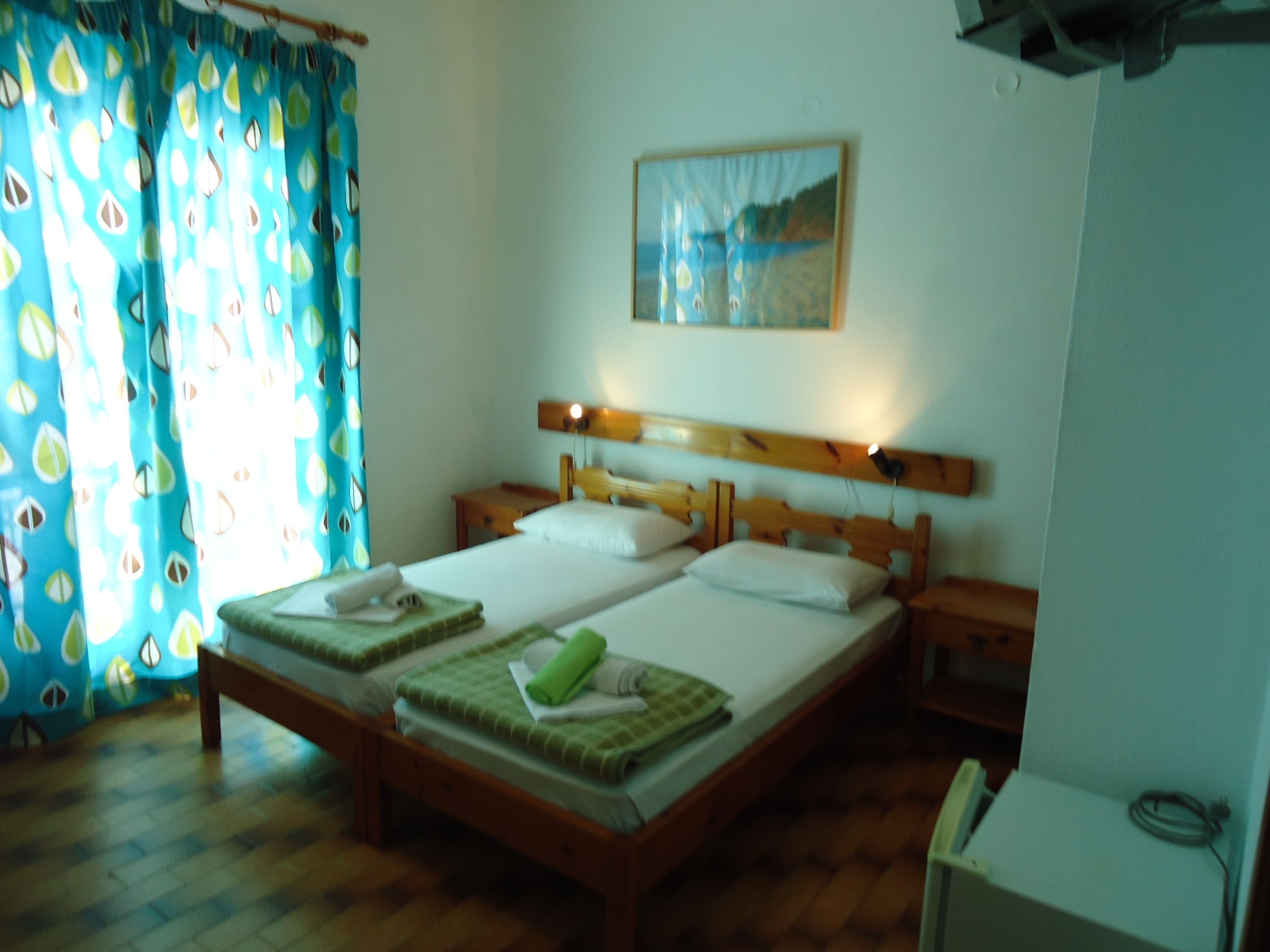 Uma cama de casal com duas almofadas, uma cabeceira de madeira e uma mesa de cabeceira com abajur.