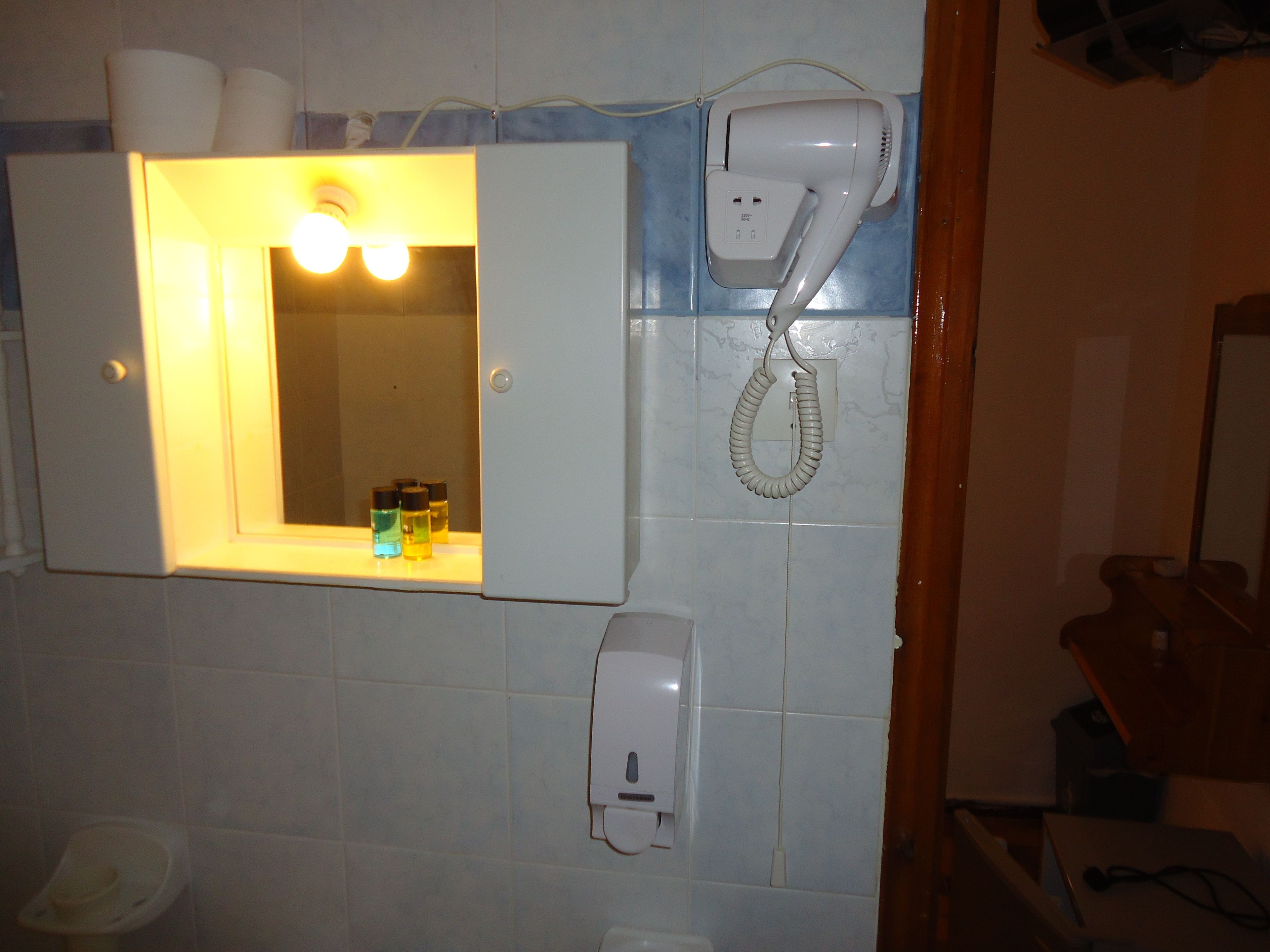 A bathroom with a mirror, a hairdryer, and a hand dryer on the wall.