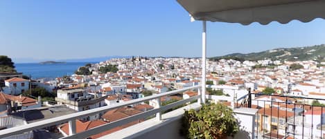 A balcony with a view of a coastal town, white buildings, and a clear blue sky.
