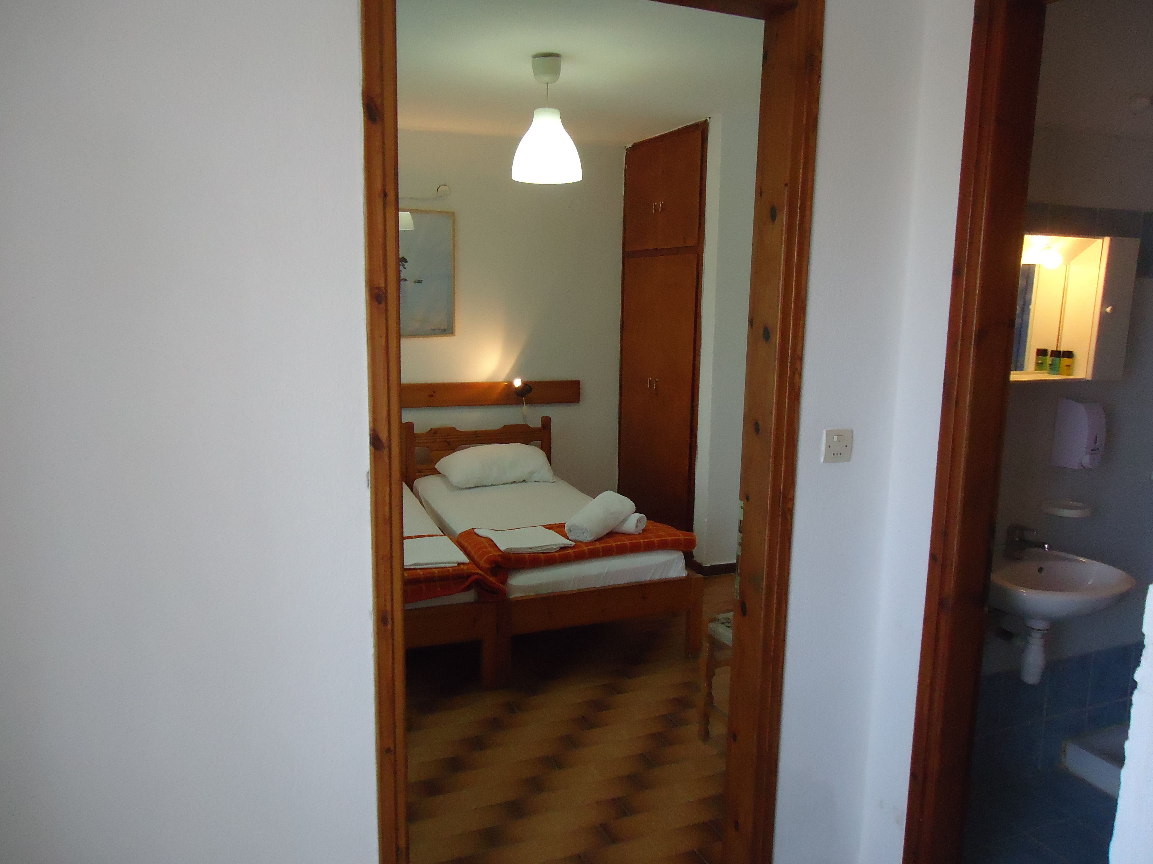 Ein Schlafzimmer mit einem hölzernen Bett, einem Schrank aus Holz, einem Nachttisch und einer Deckenleuchte.