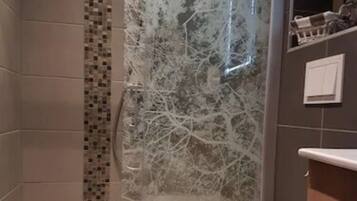 Une salle de bain comprenant un espace douche, des toilettes et un lavabo.