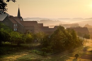A rural village with traditional houses, a church, and a misty landscape.