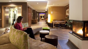 A modern hotel lobby with a fireplace, seating areas, and a visible elevator. - SPA Hôtel Au Lion D'Or (La Petite-Pierre)