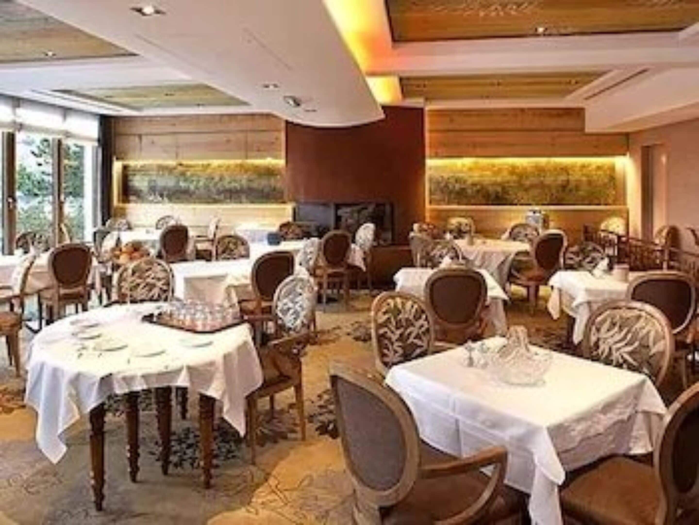 Un restaurante con mesas redondas, sillas y un amplio ventanal.