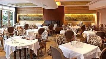 Un restaurante con mesas redondas, sillas y un amplio ventanal.