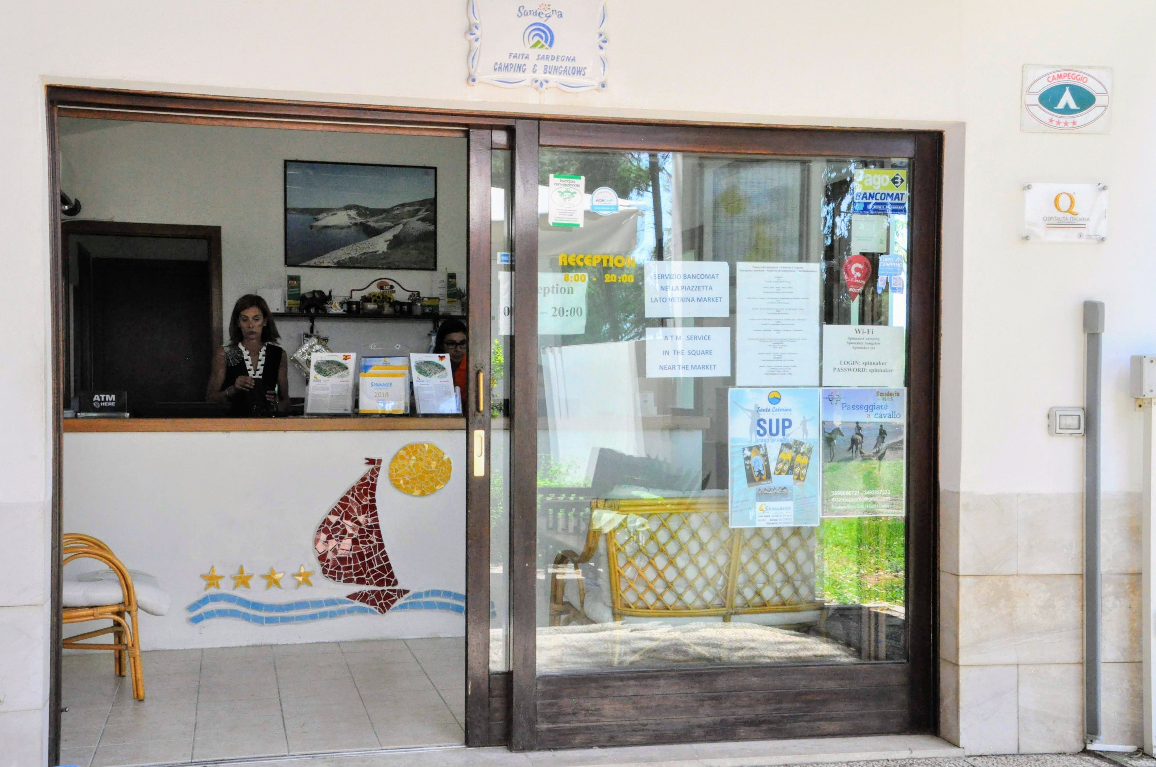 A reception area with a reception desk, a chair, and a wall with a mosaic design.