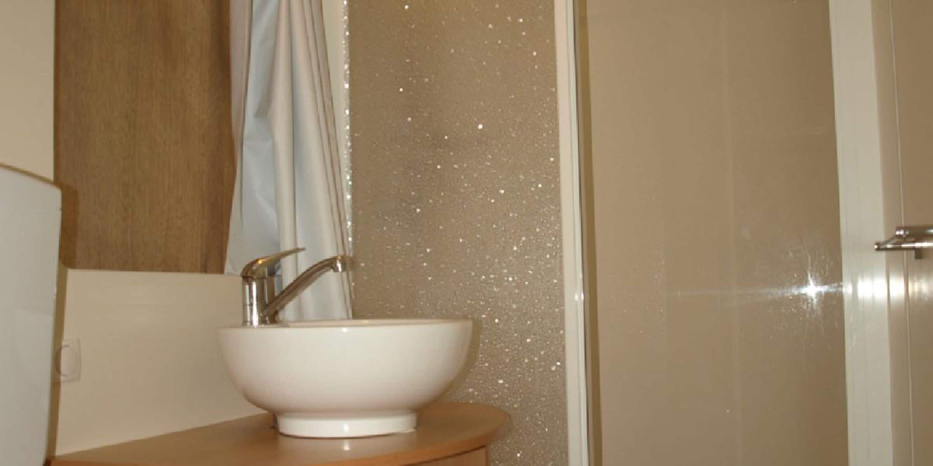 Un baño con lavamanos blanco, espejo y cortina de ducha.