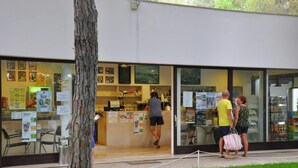 Fachada con mostrador, ventanas de vidrio y varios letreros.