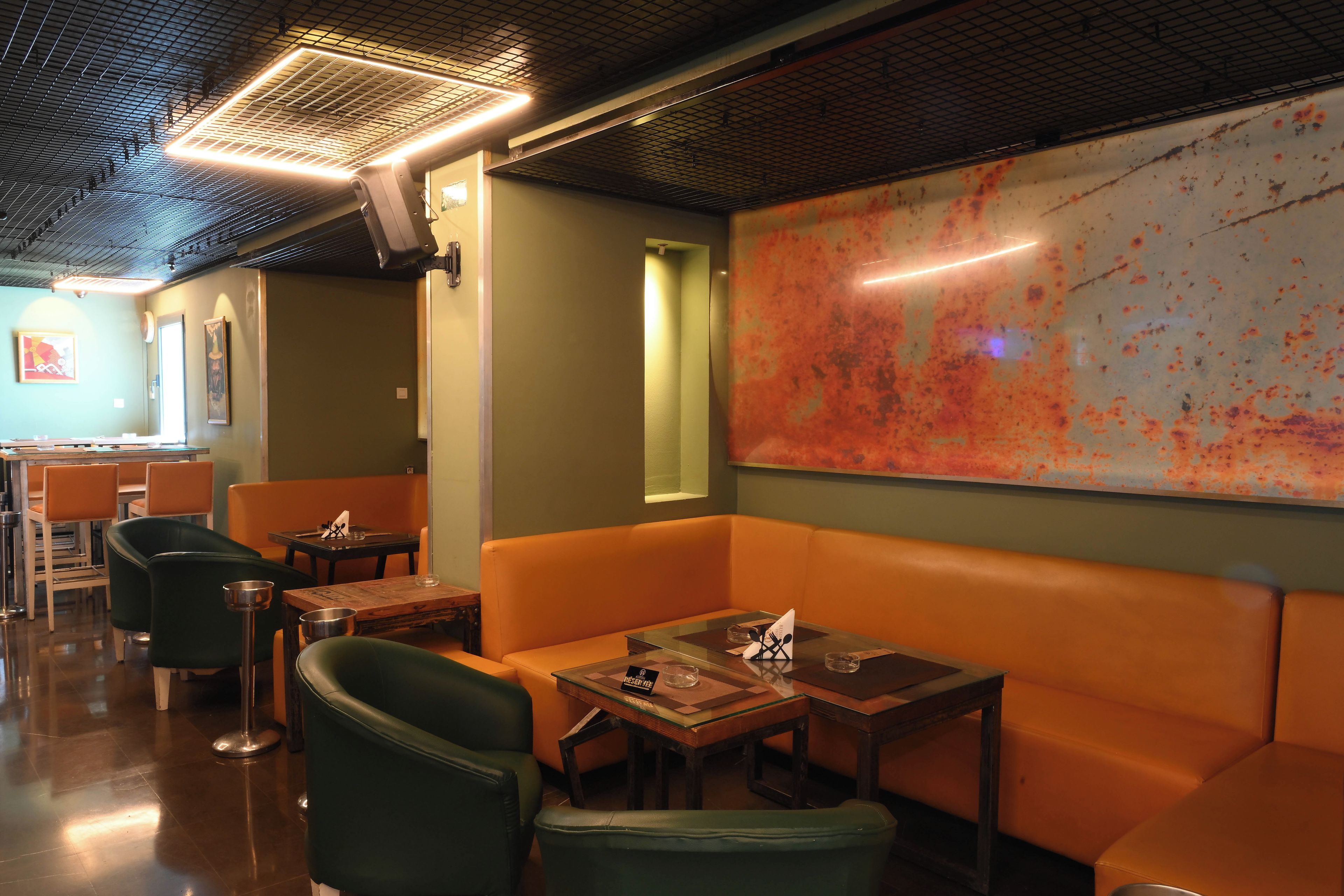 Ein Restaurantinneres mit Sitzecken, Tischen und einem großen, abstrakten Gemälde an der Wand.