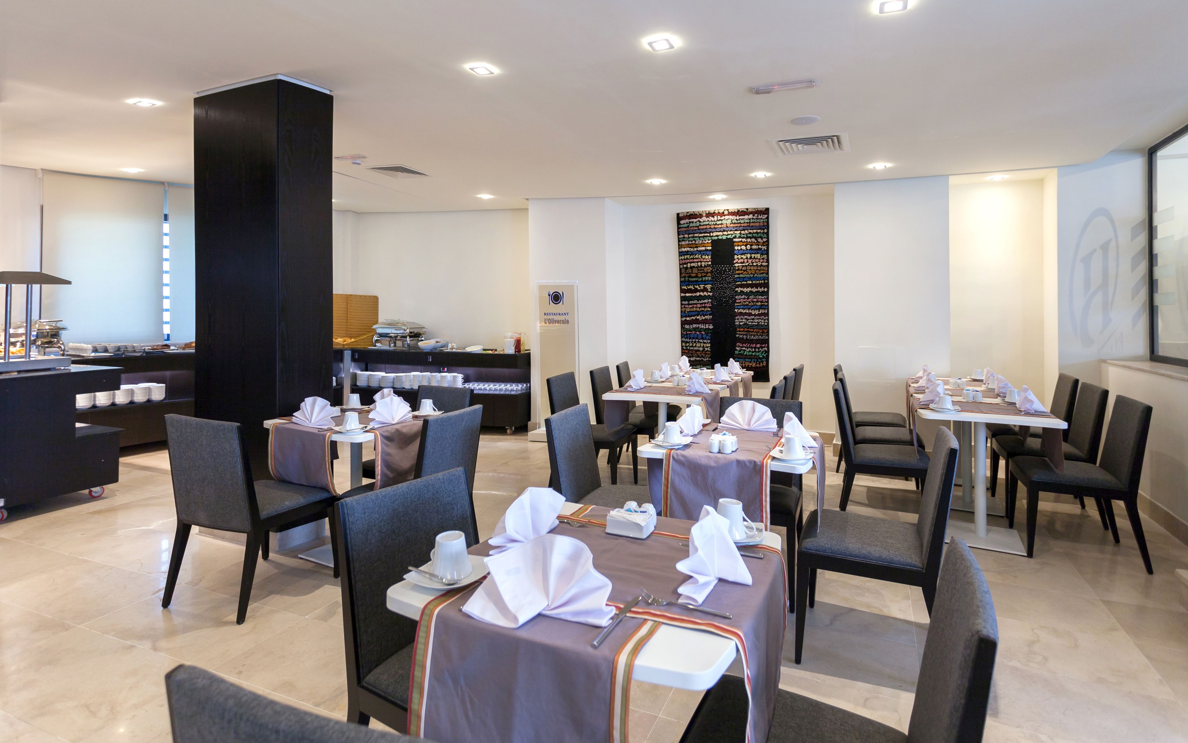 Un restaurante con mesas dispuestas para comer, una zona de bufé y una barra con alimentos.