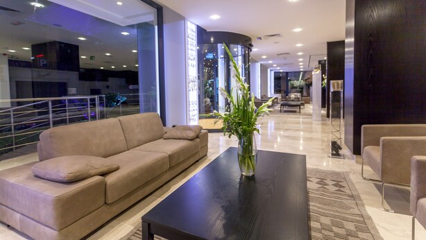 A modern lobby with a beige sofa, a black coffee table, and a vase of flowers. - Business Hotel Tunis (Tunis)