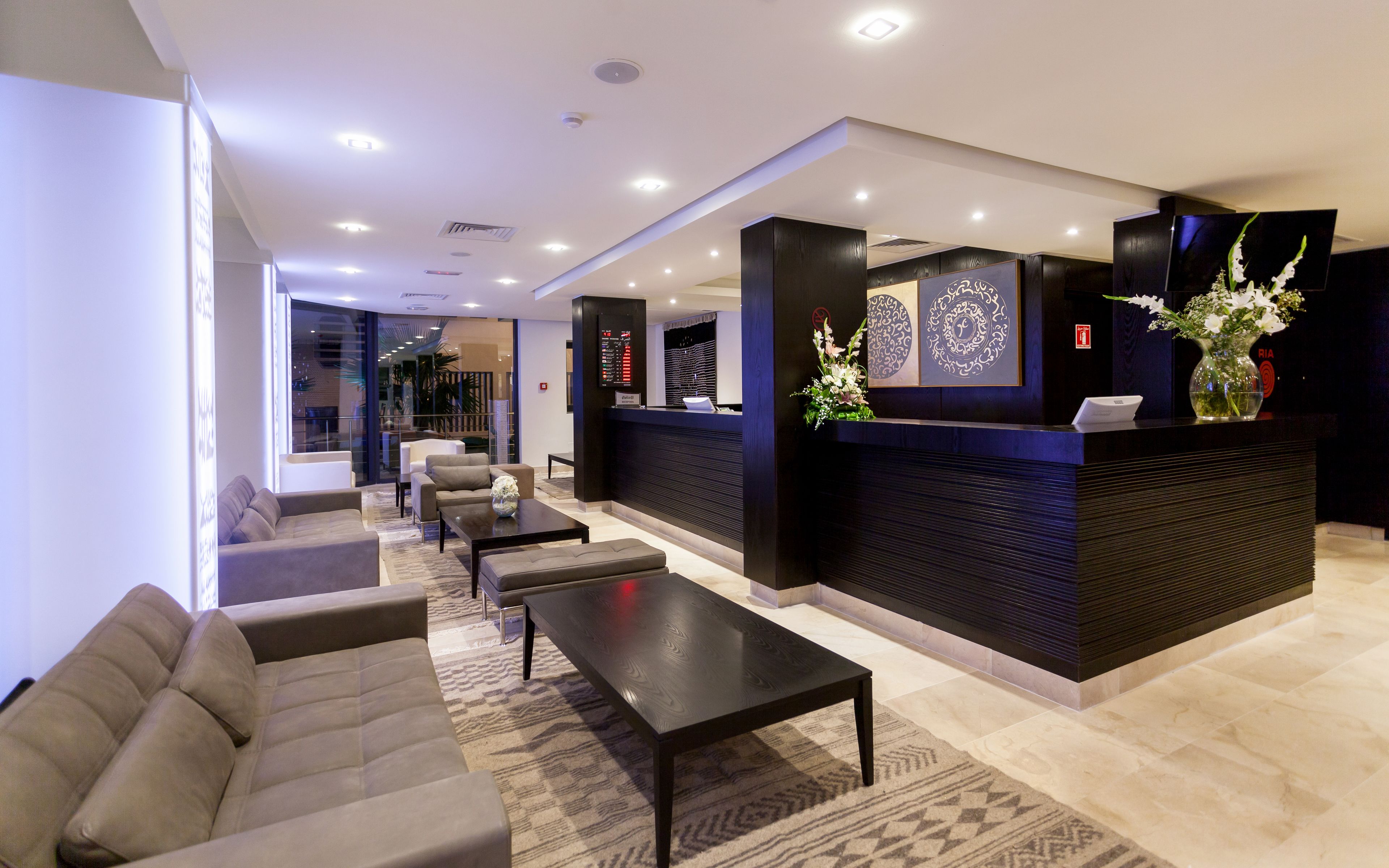 A modern lobby with a reception desk, seating area, and a view of the interior space.