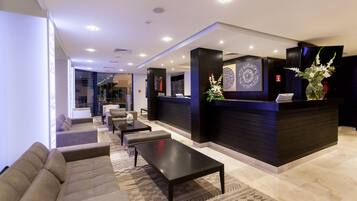 A modern lobby with a reception desk, seating area, and a view of the interior space.