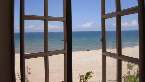 A view through open windows of a beach with clear skies. - River Ray Estates (Ho Chi Minh City)