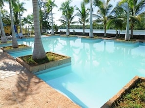 A pool area with multiple rectangular sections, surrounded by palm trees and a clear sky. - River Ray Estates (Ho Chi Minh City)