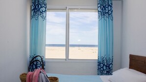 Ein Schlafzimmer mit einem Bett, einem Fenster mit Meerblick und einem Wäschekorb.