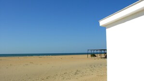 Blick auf einen Strand mit einem weißen Gebäude und einer Holzkonstruktion.