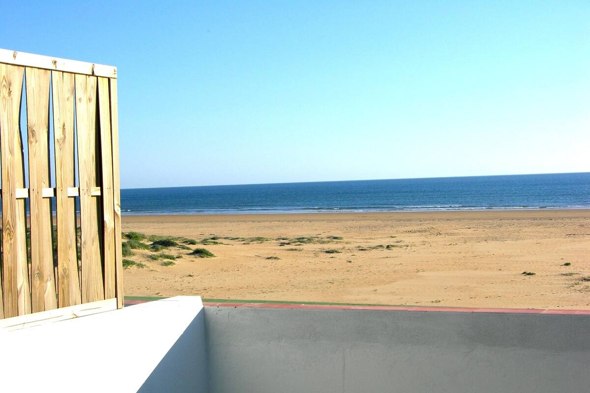 Une vue sur la plage, avec une clôture en bois et un mur en béton.