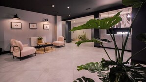 A modern hotel lobby with a seating area, framed artwork on the walls, and a reception desk. - U-Hotel Dario Lugo (Lugo)