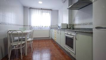 A kitchen with white cabinets, a white countertop, a stove, and a dining table with chairs.