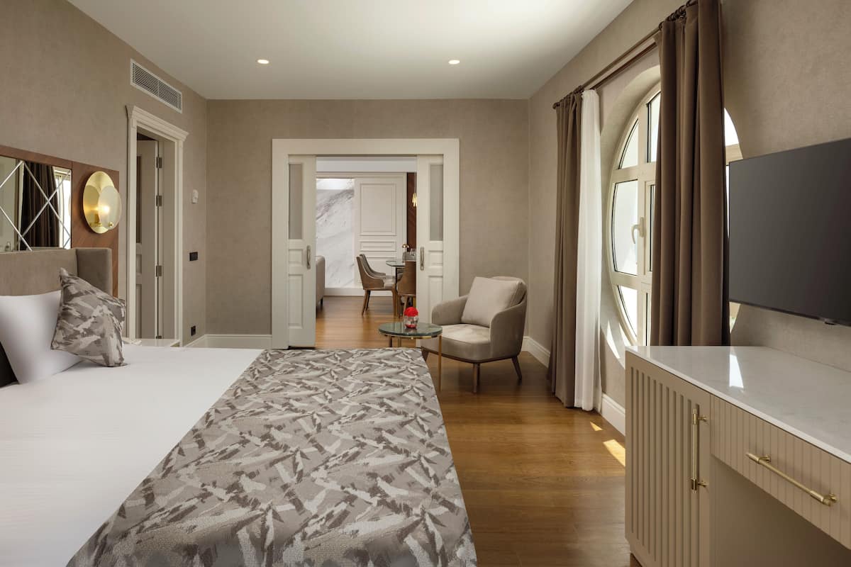 A hotel room with a bed, a TV, a desk, and a chair.