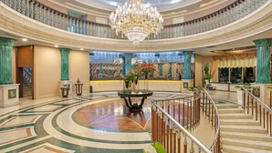 A grand lobby with a central chandelier, a round table with flowers, and a staircase leading to an upper level. - DOBEDAN BEACH RESORT COMFORT (Manavgat)