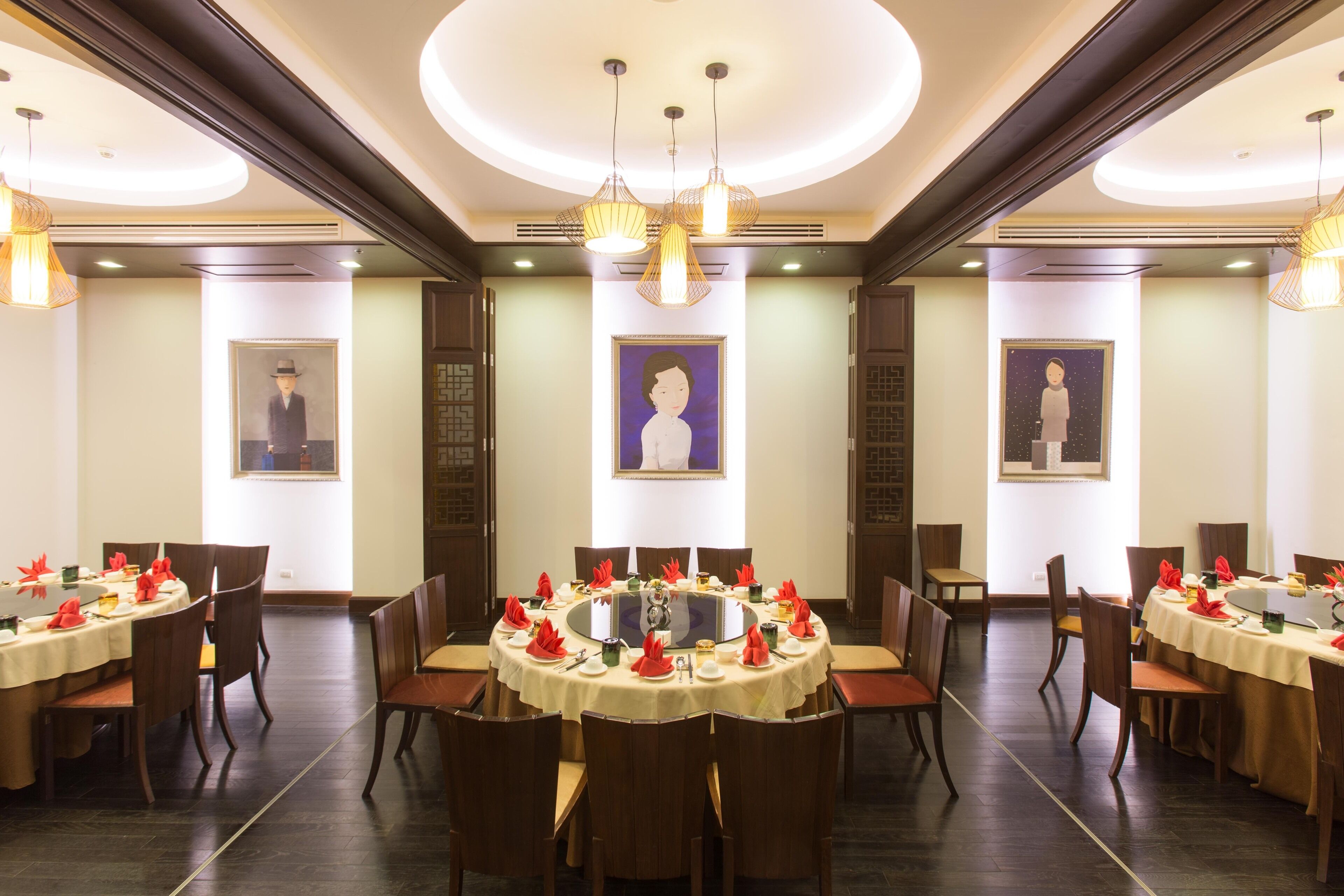 Un comedor de hotel con mesas redondas, sillas y candelabros.