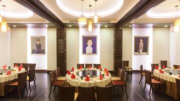 Un comedor de hotel con mesas redondas, sillas y candelabros.
