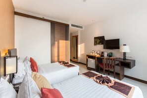 Une chambre d’hôtel avec deux lits, un bureau, une chaise, une télévision et une lampe de bureau.