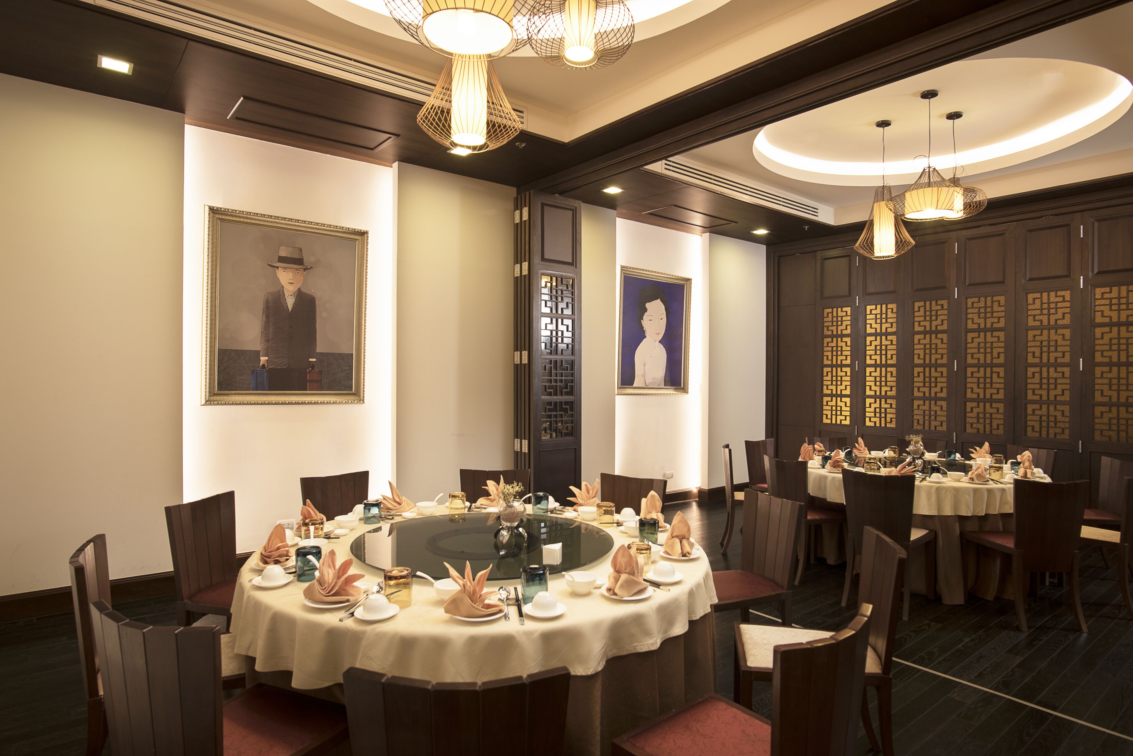 Une salle à manger élégante, avec des tables rondes, des chaises et un lustre central.