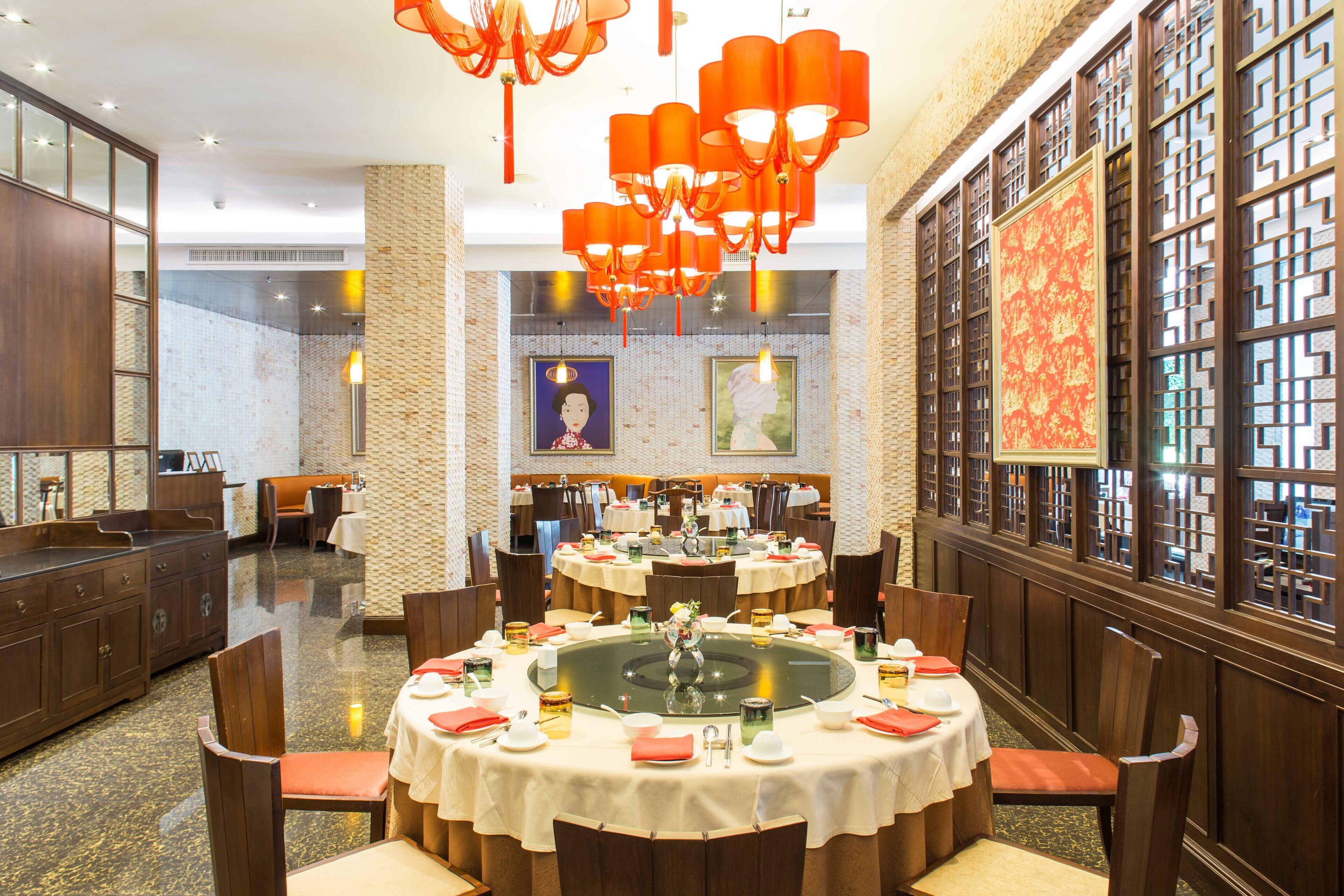 A restaurant with round tables set for dining, a central decorative piece, and traditional decor.