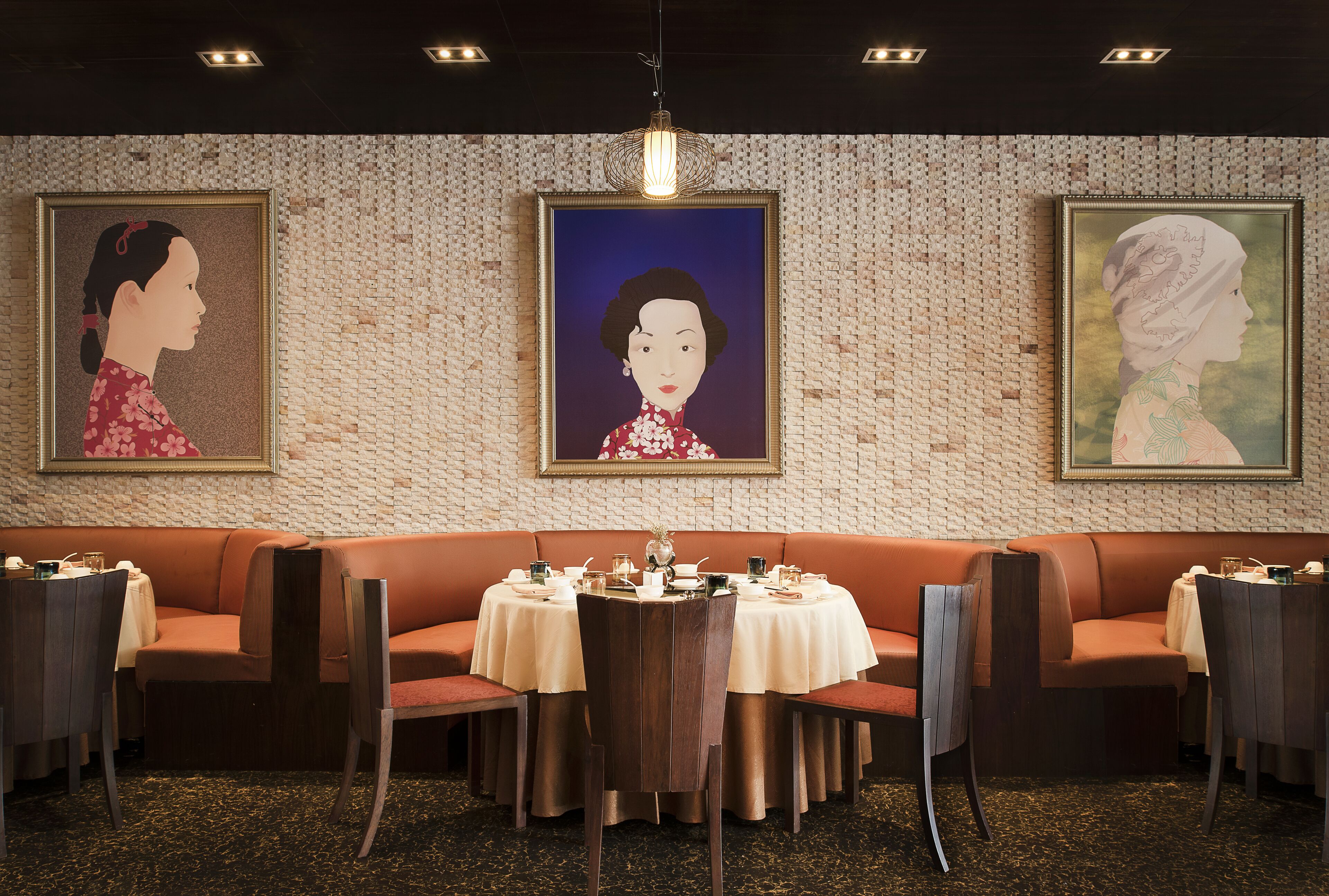 Un restaurante con pared de ladrillo, obras de arte enmarcadas, una mesa redonda con sillas y un banco acolchado.