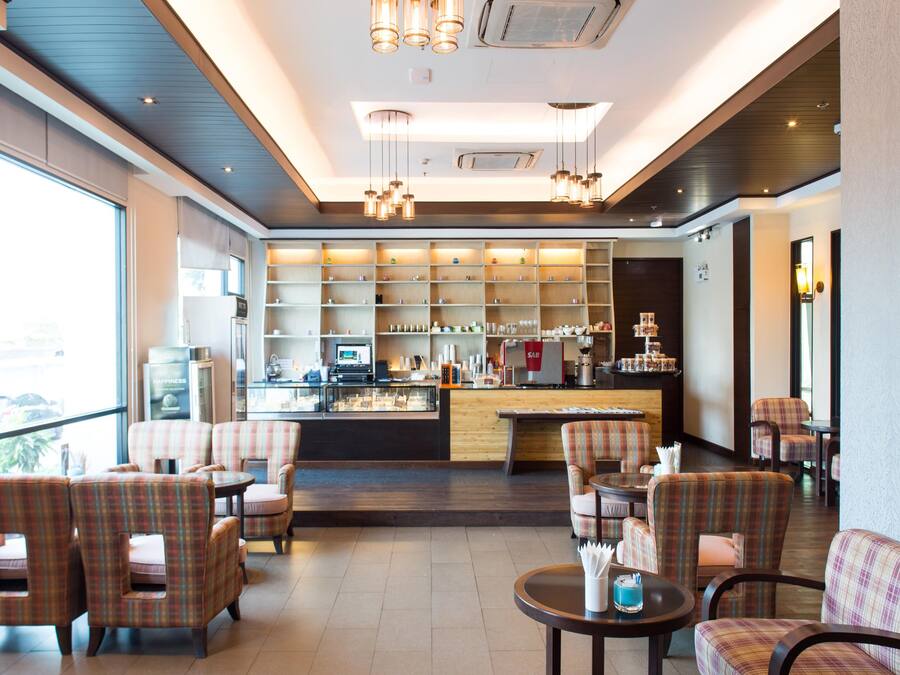 Un moderno vestíbulo de hotel con zona de bar, asientos y vistas al exterior.
