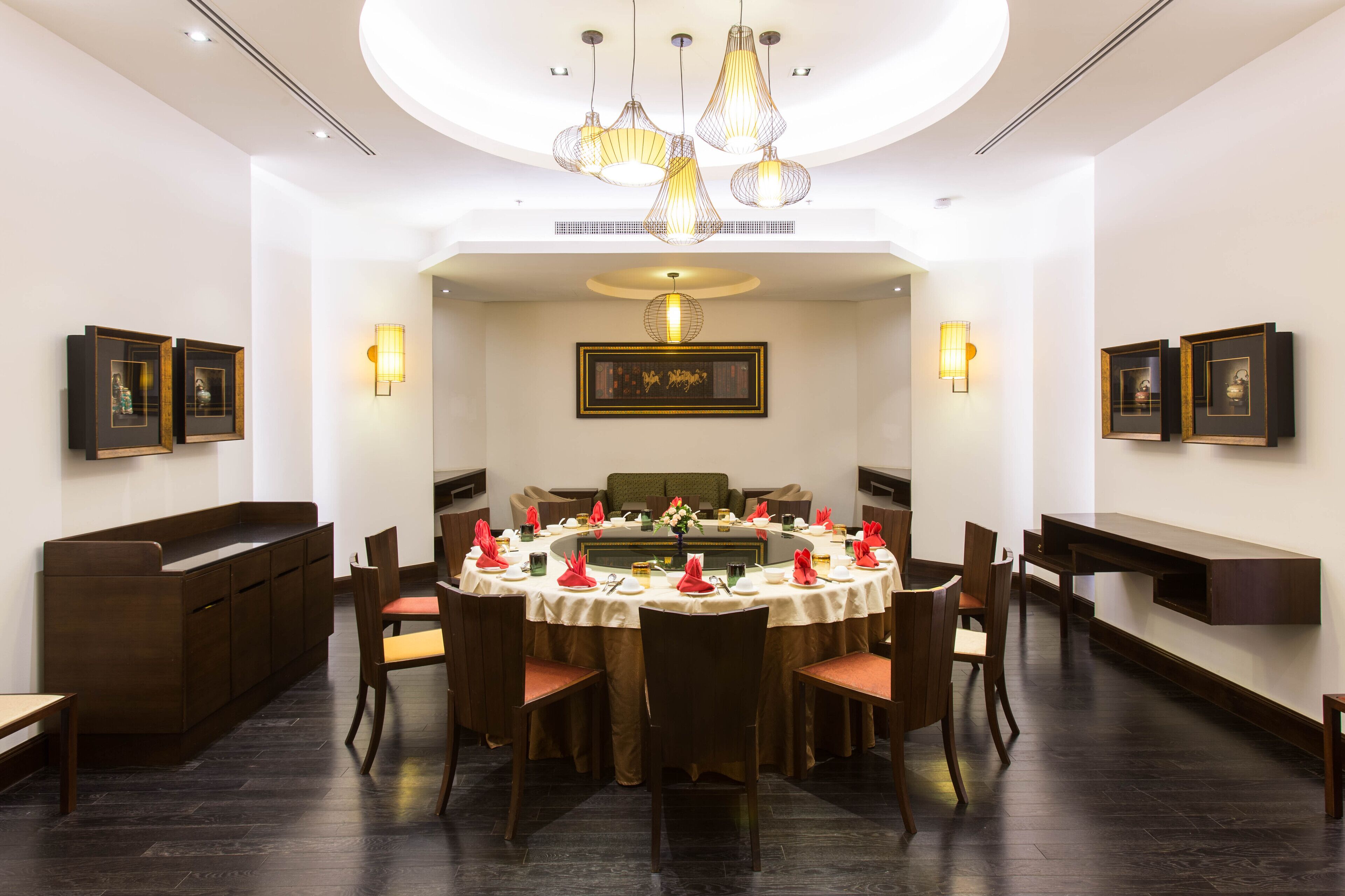Un comedor con una mesa redonda dispuesta para varias personas, rodeada de sillas de madera.