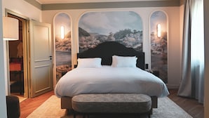 A bedroom with a large bed, a bench, a door, and a wall mural. - Domaine d'Auriac (Carcassonne)