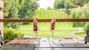 A table set with wine glasses and napkins, overlooking a lush green landscape. - Domaine d'Auriac (Carcassonne)