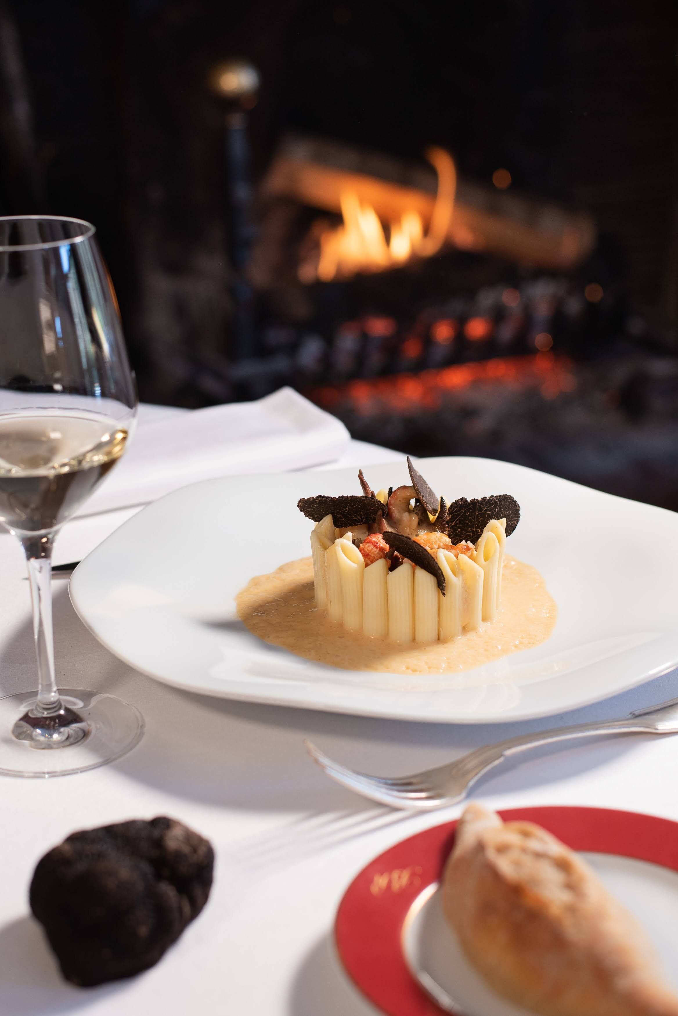 Un dessert servi dans une assiette blanche, accompagné d’un verre de vin blanc.