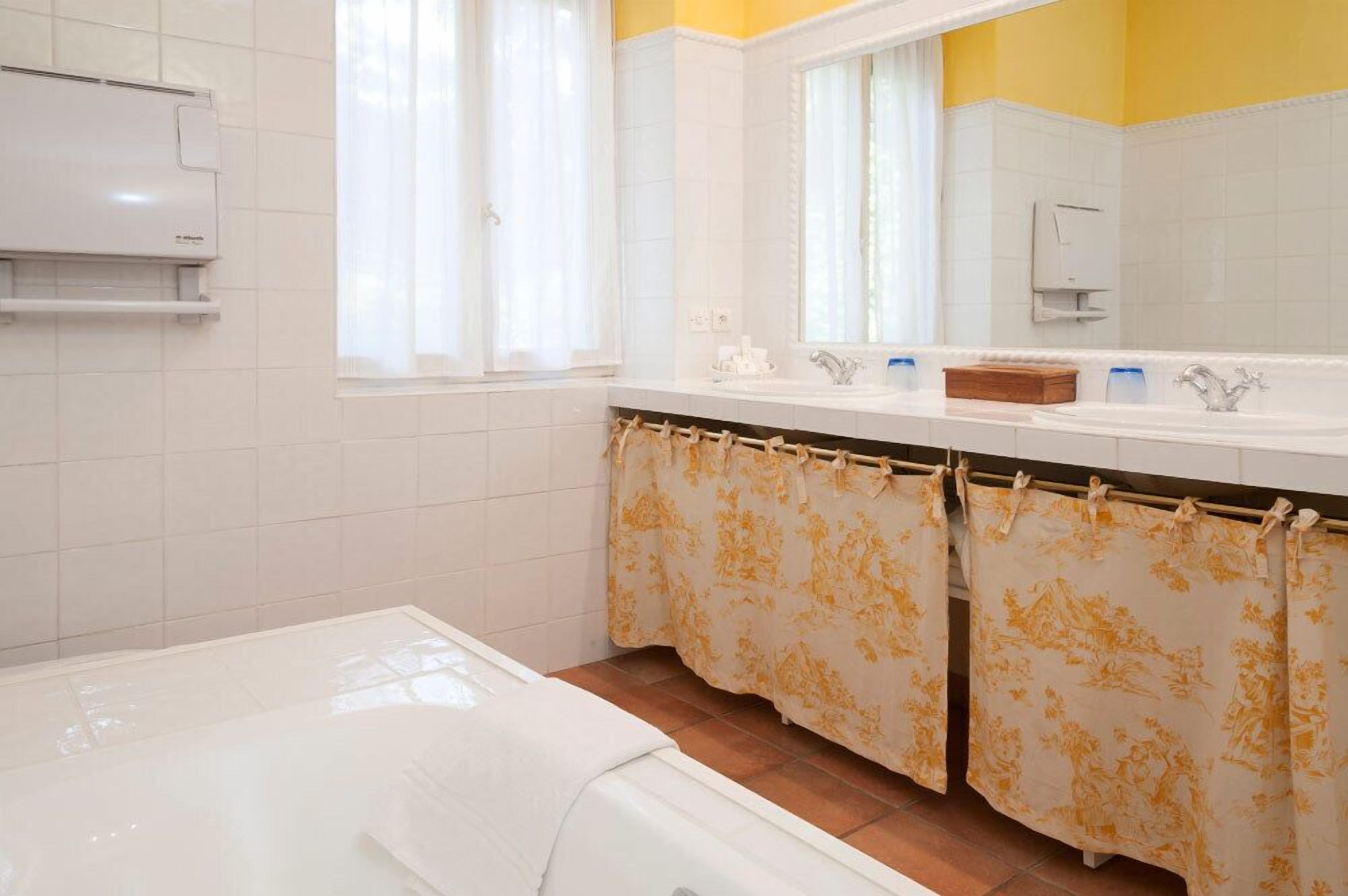 Ein Badezimmer mit einem weißen Waschbecken, einem Spiegel und einem Duschvorhang mit Blumenmuster.